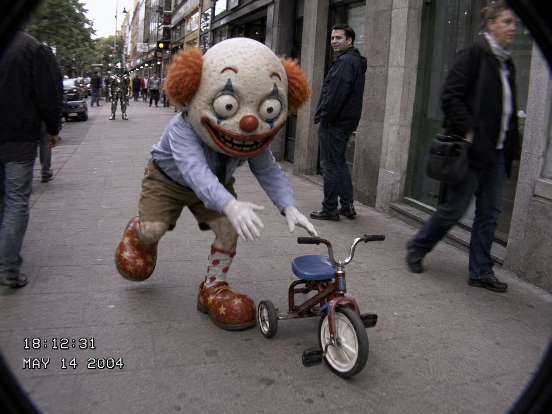 CLOWN reaching for a tricycle